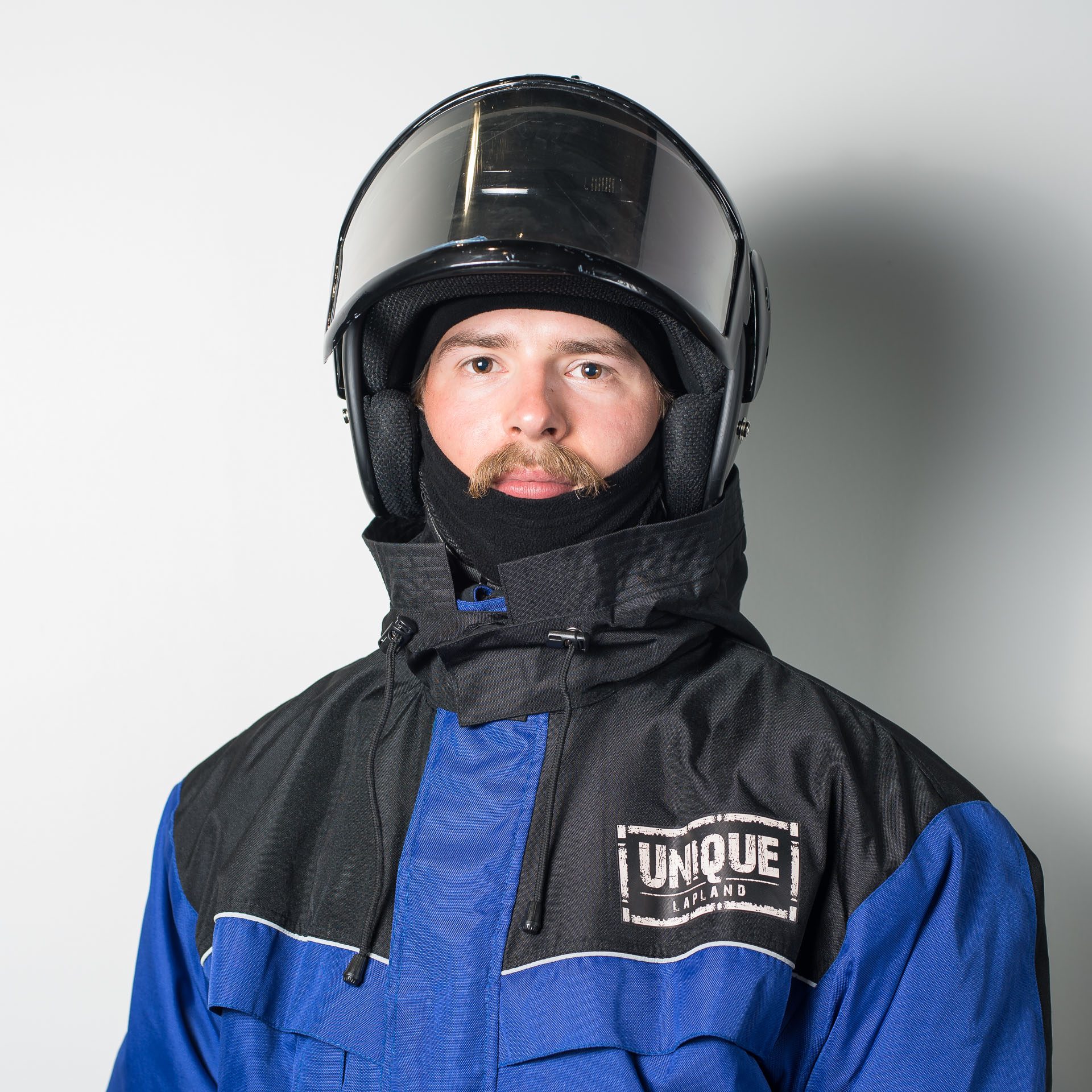 Close-up of a man wearing winter overall suit with snowmobile helmet. Outfit rental, dressing - Wild Nordic Finland