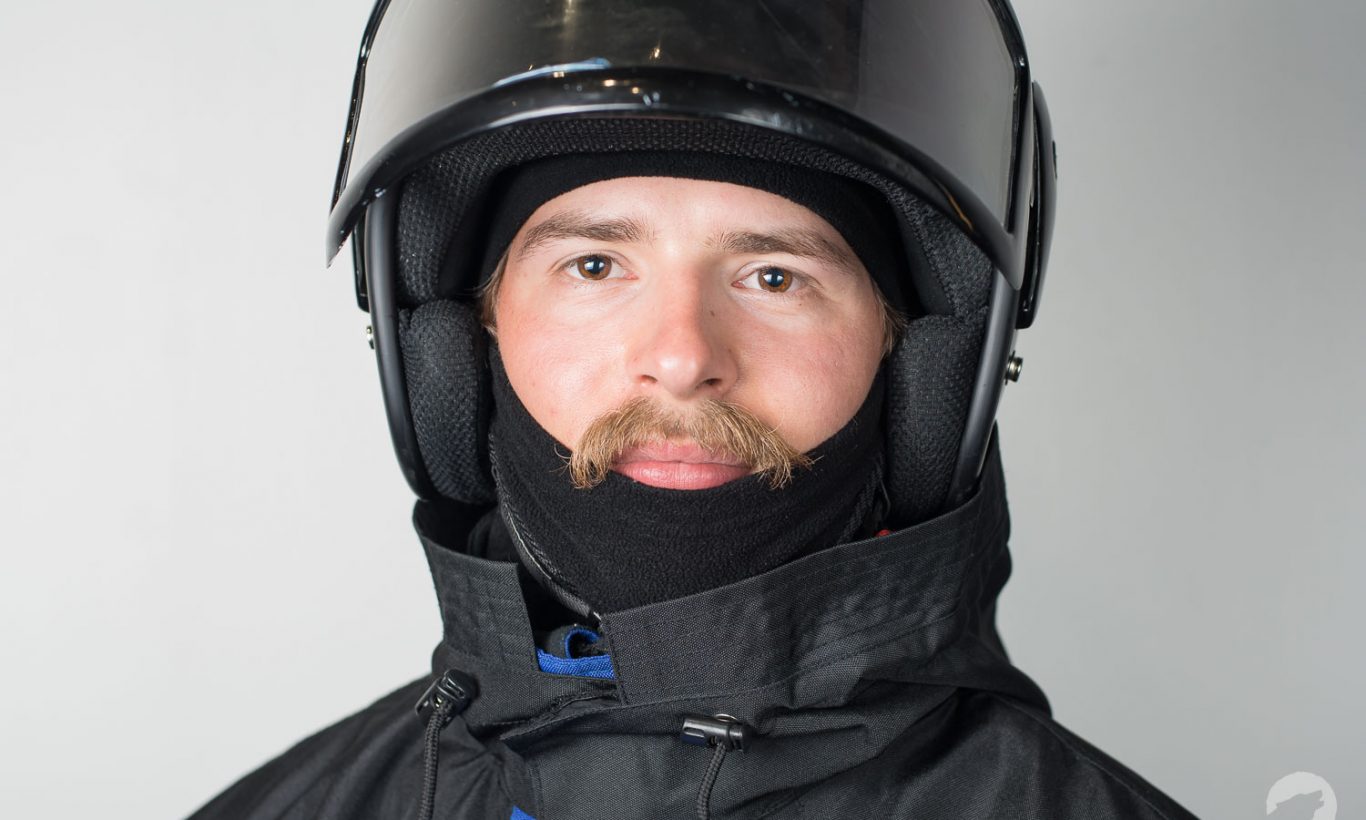 Close-up of a man wearing winter overall suit with snowmobile helmet. Outfit rental, dressing - Wild Nordic Finland