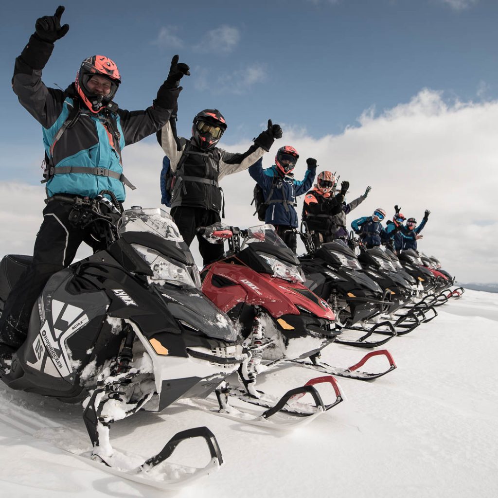 Many people cheering while standing on snowmobiles. Rovaniemi / Arctic Expeditions – Russian Border Adventure, Wild Nordic Finland @wildnordicfinland
